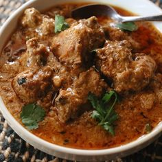 a white bowl filled with meat and garnished with cilantro