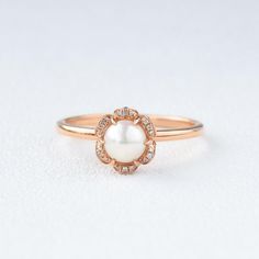 a pearl and diamond ring on a white surface