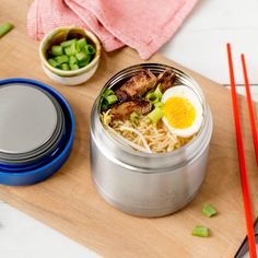 a wooden cutting board topped with food and chopsticks