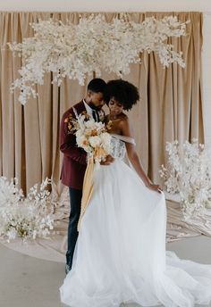 a bride and groom standing in front of an arrangement of flowers at their wedding reception