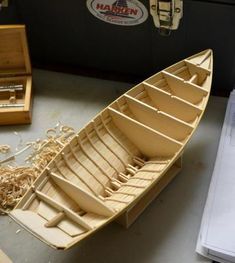 a wooden boat sitting on top of a table next to a box and some other items