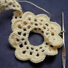 a crocheted piece of yarn with a pair of scissors next to it on a blue surface