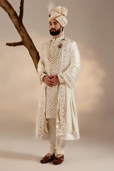 White full sleeves sherwani in linen silk base with all over Kashmiri Jamawar embroidery highlighted wih dabka and zari. Paired with full sleeves plain kurta, churidar, safa and embroidered border stole.
Components: 5
Pattern: Embroidery
Type Of Work: Zari, Dabka
Neckline: Band
Sleeve Type: Long
Fabric: Linen Silk
Color: White
Other Details: 
Closure: 
Sherwani: Front hooks
Kurta: Front placket buttons
Note: The jewellery and kalangi worn by the model is not for sale
Occasion: Groom - Aza Fashio White Sherwani, Jatin Malik, Seema Gujral, Embroidered Sherwani, Blouse Yoke, Dhoti Pants, Royal Look, Indian Wedding Outfits, Pashmina Shawl