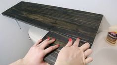 a woman with red nail polish on her nails is using a wooden plank to make a counter top