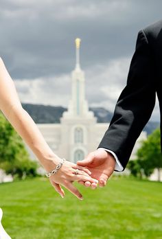 a bride and groom hold hands in front of the mormon temple on their wedding day