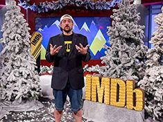 a man standing in front of snow covered trees on the set of tv talk show