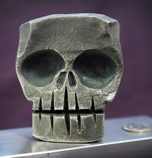 a silver skull statue sitting on top of a metal table next to a purple wall