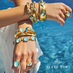 two women's hands with rings and bracelets on their wrists near the water