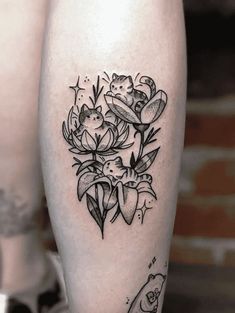 a black and white tattoo on the leg of a woman with flowers around her ankles