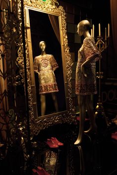 mannequins in front of a large mirror with candles on the table next to it