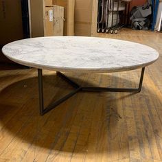 a white marble coffee table sitting on top of a hard wood floor next to a pile of boxes