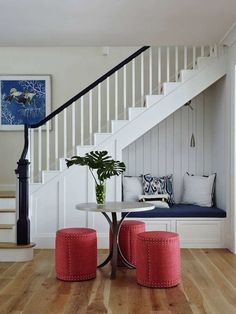 there is a table and two stools on the floor in front of the stairs