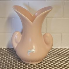 a pink vase sitting on top of a tiled floor