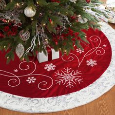 a christmas tree skirt with snowflakes and ornaments on the floor next to it