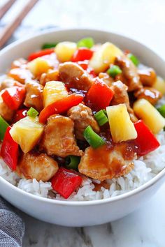 a white bowl filled with rice, meat and pineapples on top of it