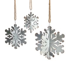 three metal snowflakes hanging from twine strings on a white background,