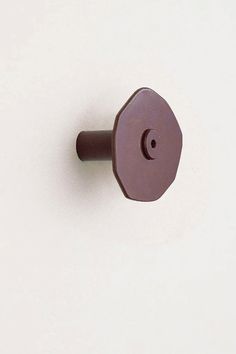 a brown door knob on a white wall with a small hole in the top left corner