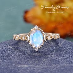 Moon Stone Wedding Ring, Celestial Wedding Jewelry With Halo, Celestial Moonstone Halo Ring For Wedding, Celestial Halo Moonstone Wedding Ring, Celestial Halo Moonstone Ring For Weddings, Celestial Style Oval Diamond Promise Ring, Gold Moon-shaped Crystal Wedding Ring, Elegant Crescent Moonstone Jewelry, Heirloom Oval Moonstone Jewelry