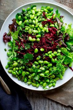 a white plate topped with green beans and lettuce on top of a wooden table