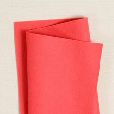 red paper folded up on top of each other with a white surface behind the edges