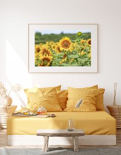 a sunflower field is shown in this white room with yellow pillows and throw pillows