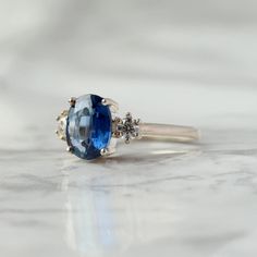 With a brilliant cut like that, this ring is nothing but pure brilliance in itself. With a lovely Kyanite, the Khloe ring with two side moissanite sparkles like there is no tomorrow. Celebrate your milestones or special occasions with this ring as the perfect gift for sisters as a best friend's gift, or just as an everyday celebration of life in general. Details: Center stone Gemstone: Kyanite Stone Shape: Oval Measurements: approx. 9x7mm Side stones Gemstone: Moissanite Shape: Round Measurement There Is No Tomorrow, Gemstone Rings Unique, Planet Ring, Kyanite Ring, No Tomorrow, Moss Agate Ring, Snow Flakes, Rose Quartz Ring, Agate Ring