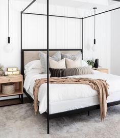 a bedroom with a four post bed and white walls