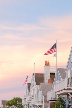 the american flag is flying in front of many houses on the water at sunset or dawn