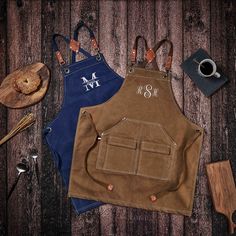 two personalized aprons on top of a wooden table with utensils and other items