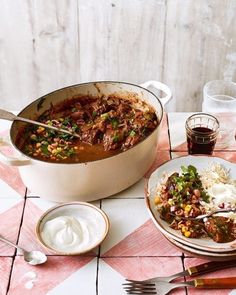 a table topped with plates of food next to a pot filled with meat and veggies