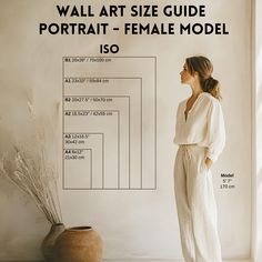 a woman standing in front of a wall with a vase next to it and the text, wall art size guide portrait - female model is so