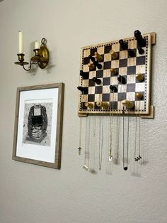 a chess board hanging on the wall next to a framed photograph and some keys attached to it