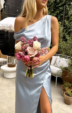 a woman in a blue dress holding a bouquet of flowers