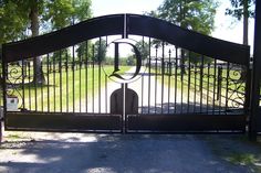 an iron gate in front of a driveway with a sign on it that says o