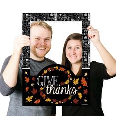 a man and woman holding up a sign that says give thanks