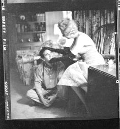 an old black and white photo of a woman getting her hair combed by a man