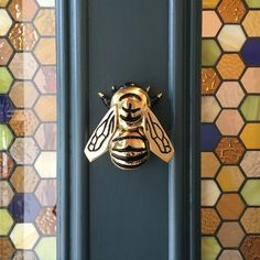 a close up of a door with a bee on it's side and colorful tiles in the background