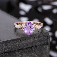 an amethoraite and diamond ring sitting on top of a wooden table