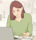 a woman sitting at a desk working on a laptop computer