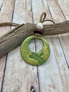 a green and white necklace with a dragon on it's disc hanging from a tree branch