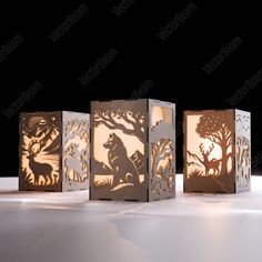 three paper lanterns with animals and trees cut out of them, on a table in the dark