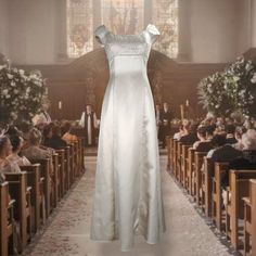 a white dress is on display in front of a church full of people and flowers