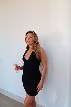 a woman in a black dress holding a glass of wine