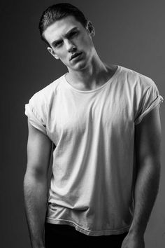 black and white photograph of a man in a t - shirt looking at the camera