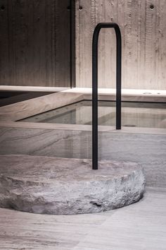 an outdoor swimming pool surrounded by stone and metal bars, with a wooden wall in the background