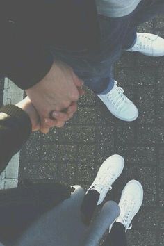 someone is holding their hands in front of the camera, and they are both wearing white sneakers