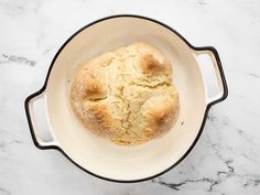 a loaf of bread in a pot on a marble counter top with a black rim