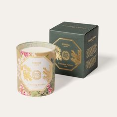 a candle in front of a box with an image of flowers and leaves on it