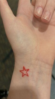 a small red star tattoo on the left wrist and right hand is shown in this image