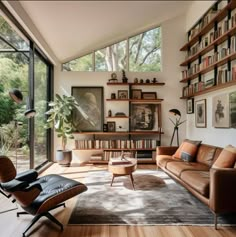 a living room filled with furniture and bookshelves next to a large glass window